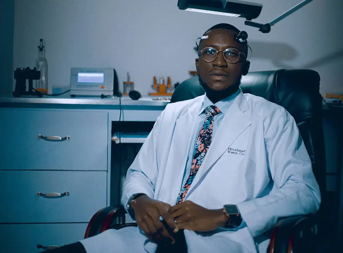 A doctor in a white coat seated in a consulting room